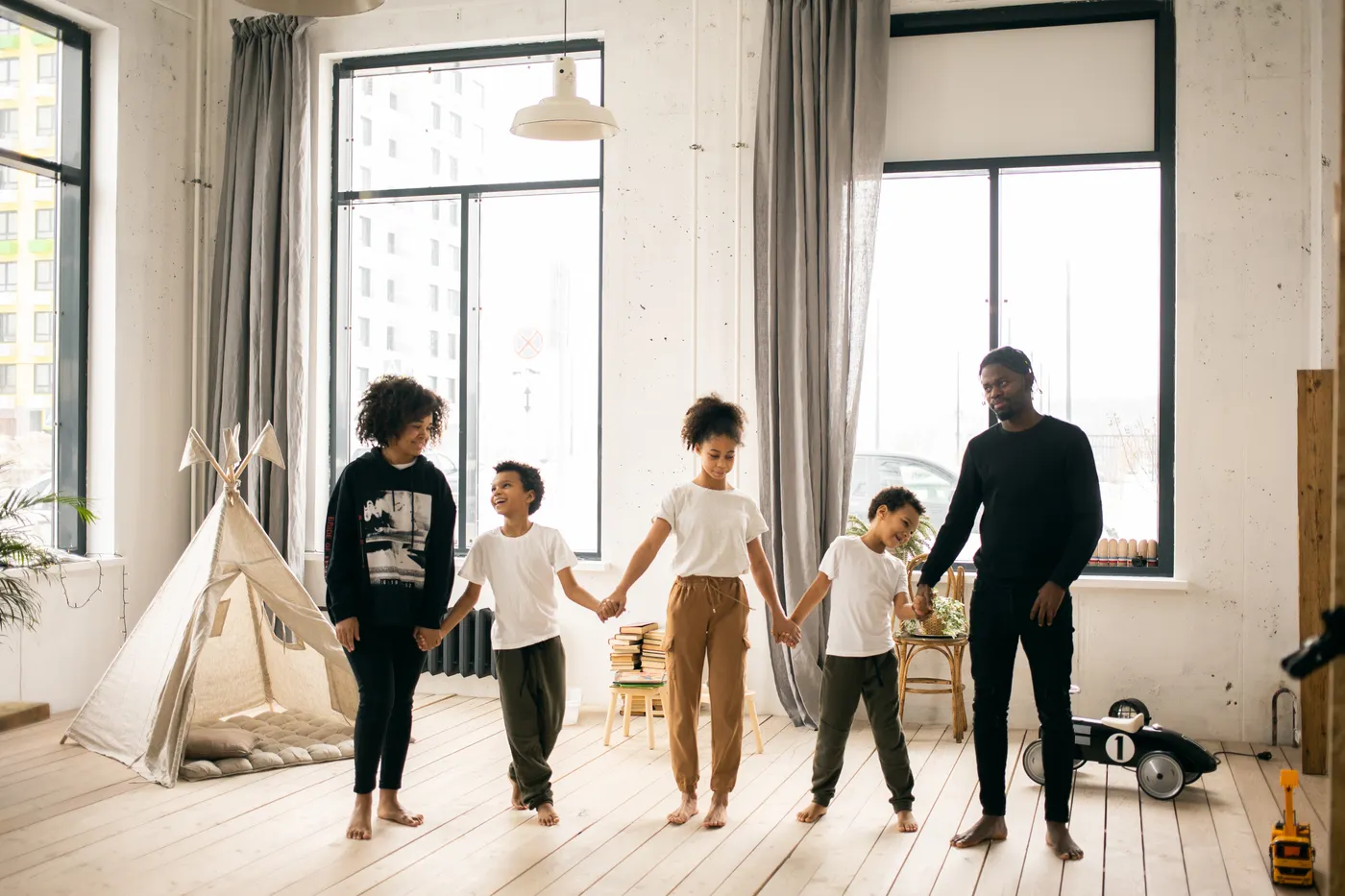 Adults and children holding hands in a living room.