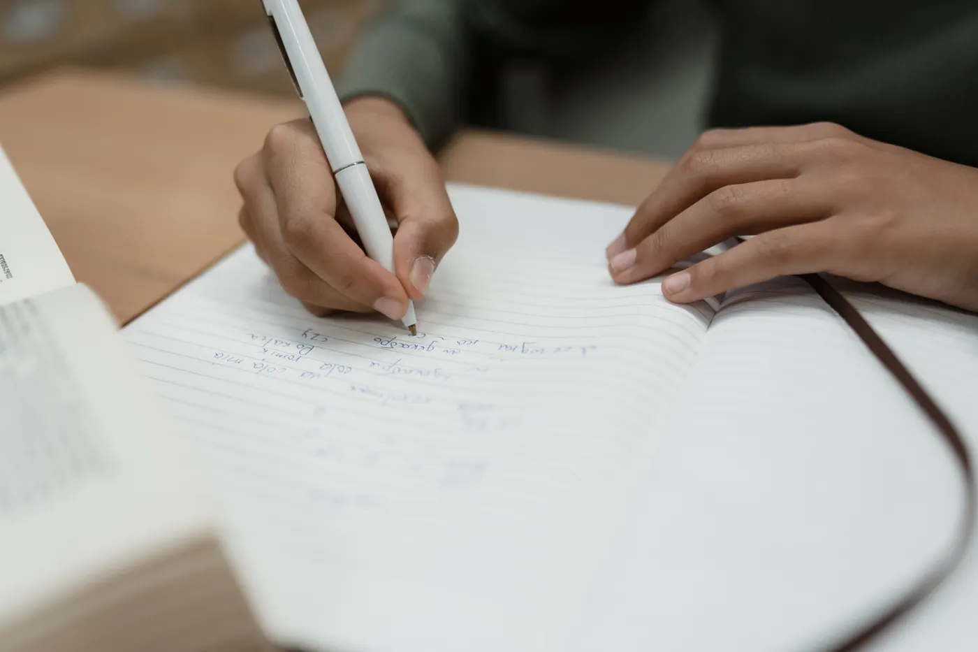 A hand writing notes in an open notebook.