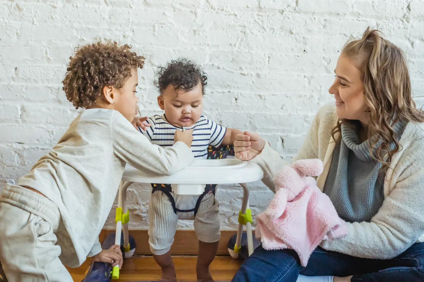 An adult playing with two children at home.