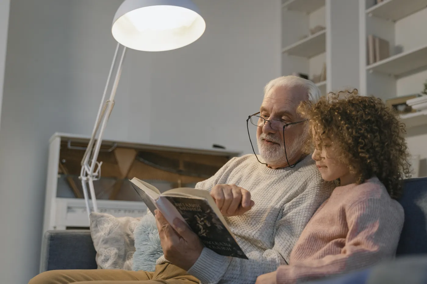 An older adult and a child reading together.