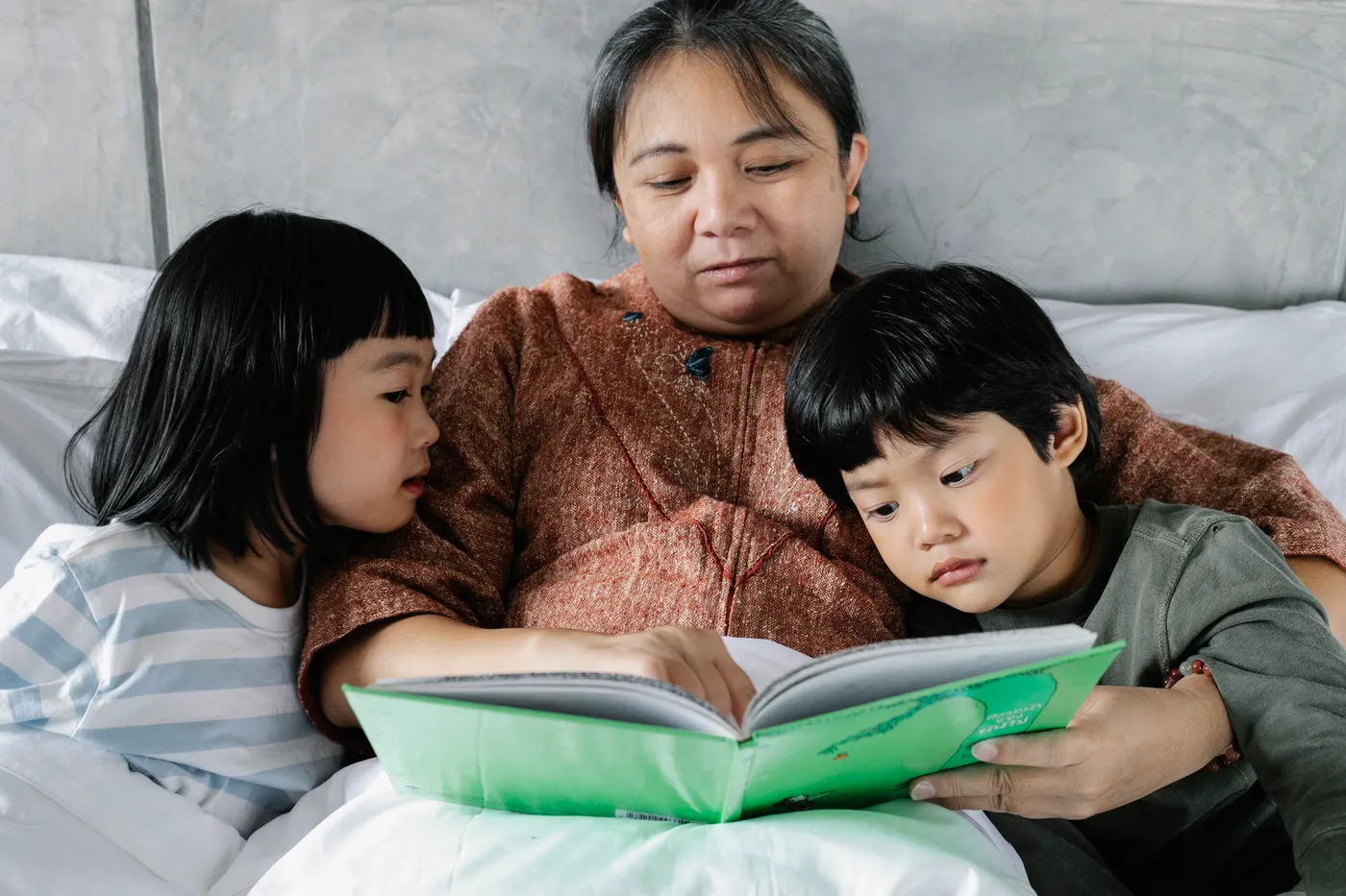 An older adult reading with two children.