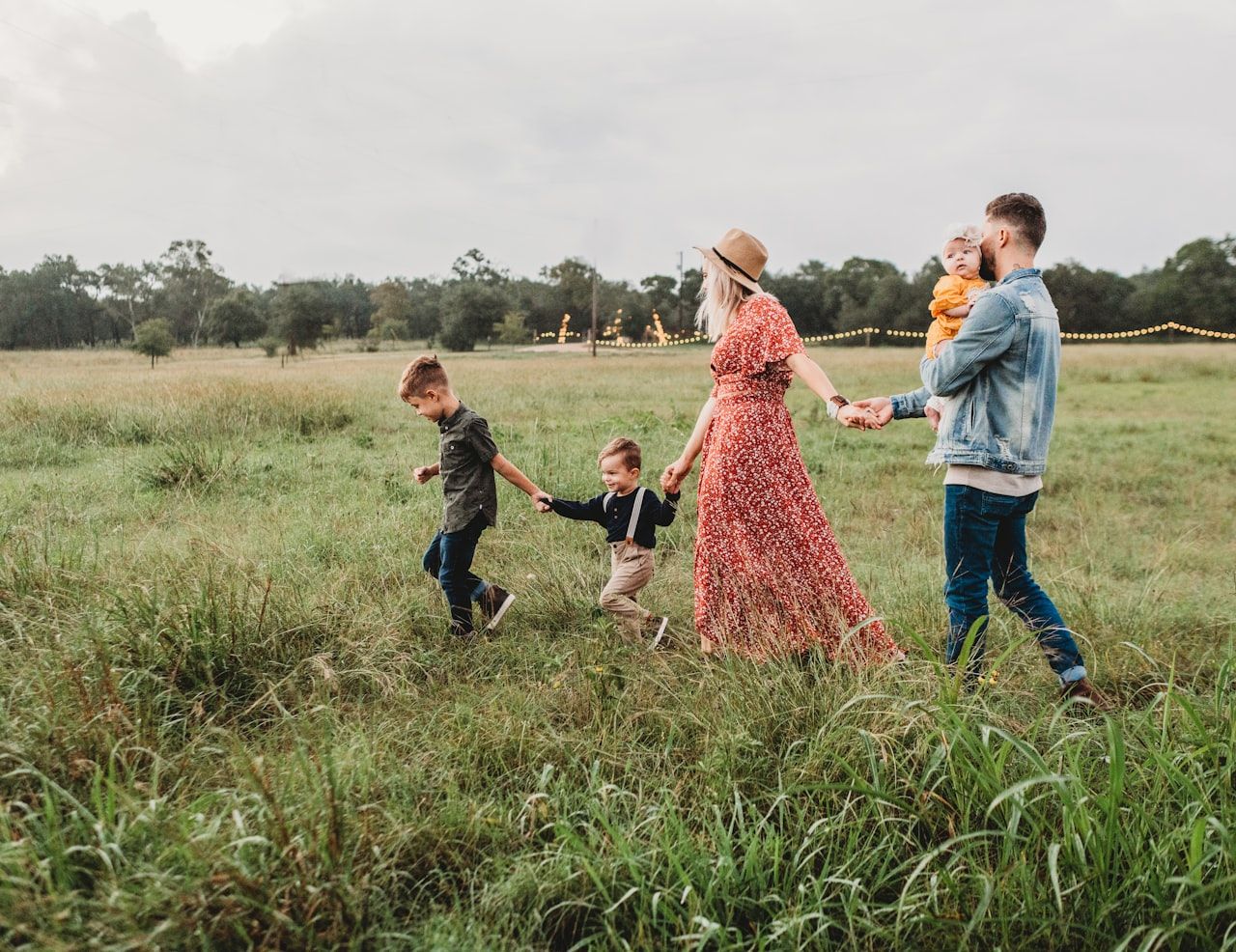 Family of five walking hand-in-hand through a sunlit meadow, representing the families we guide through the investigation process